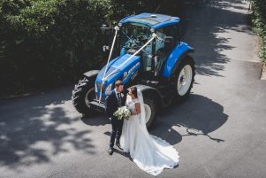 bride and groom pose in front of a tractor